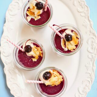 four smoothies on a white tray with blue table in the background