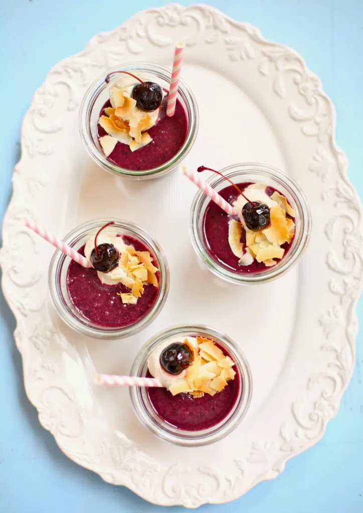 four smoothies on a white tray with blue table in the background