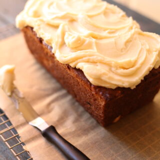 Banana bread on a table with frosting knife
