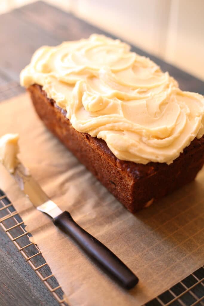 Banana bread on a table with frosting knife