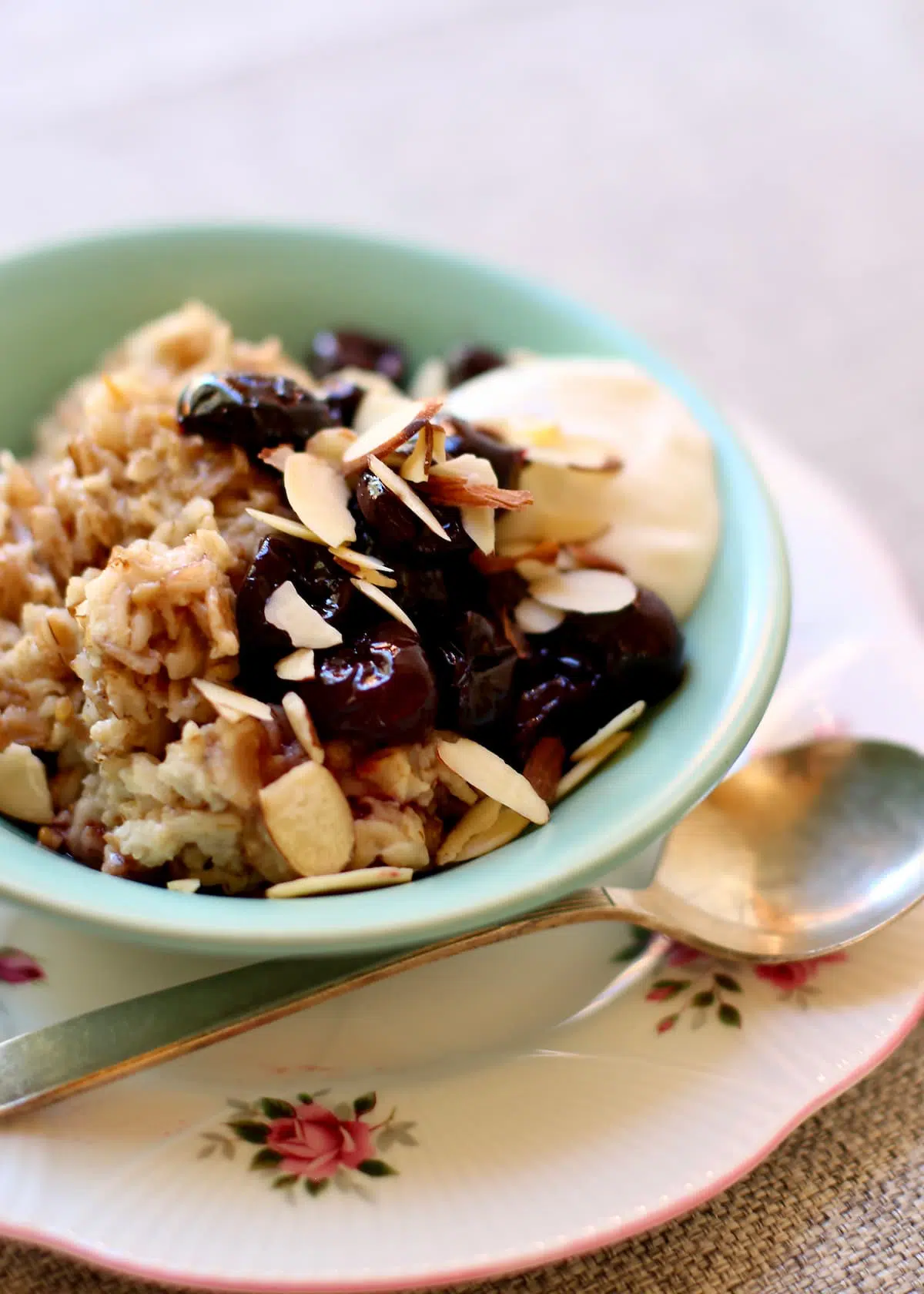 a close up shot of oatmeal with cherries on it and a dollop of plain yogurt.