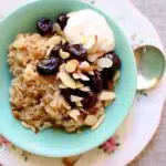 a green bowl of oatmeal with cherries and yogurt on top, with text overlay saying the recipe name.