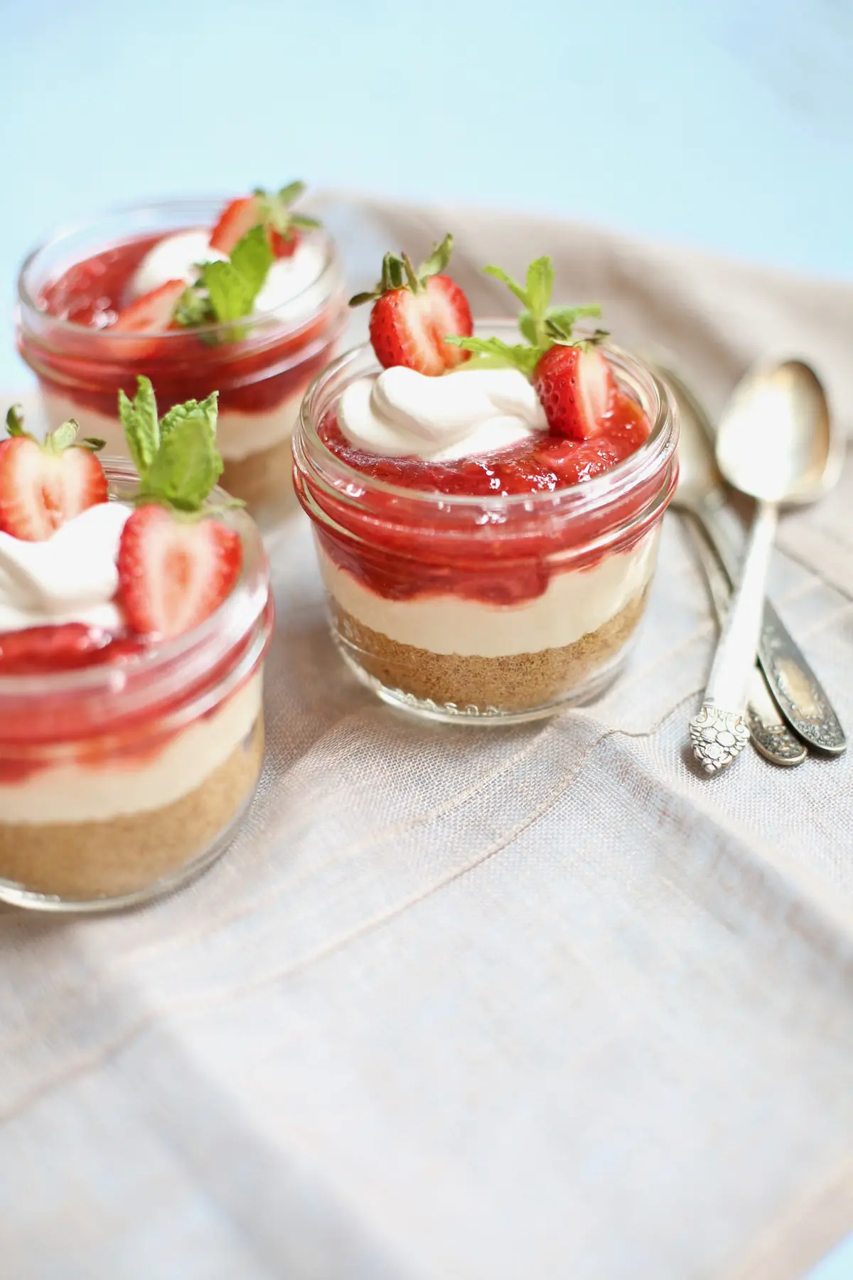 three cheesecakes and spoons on a table