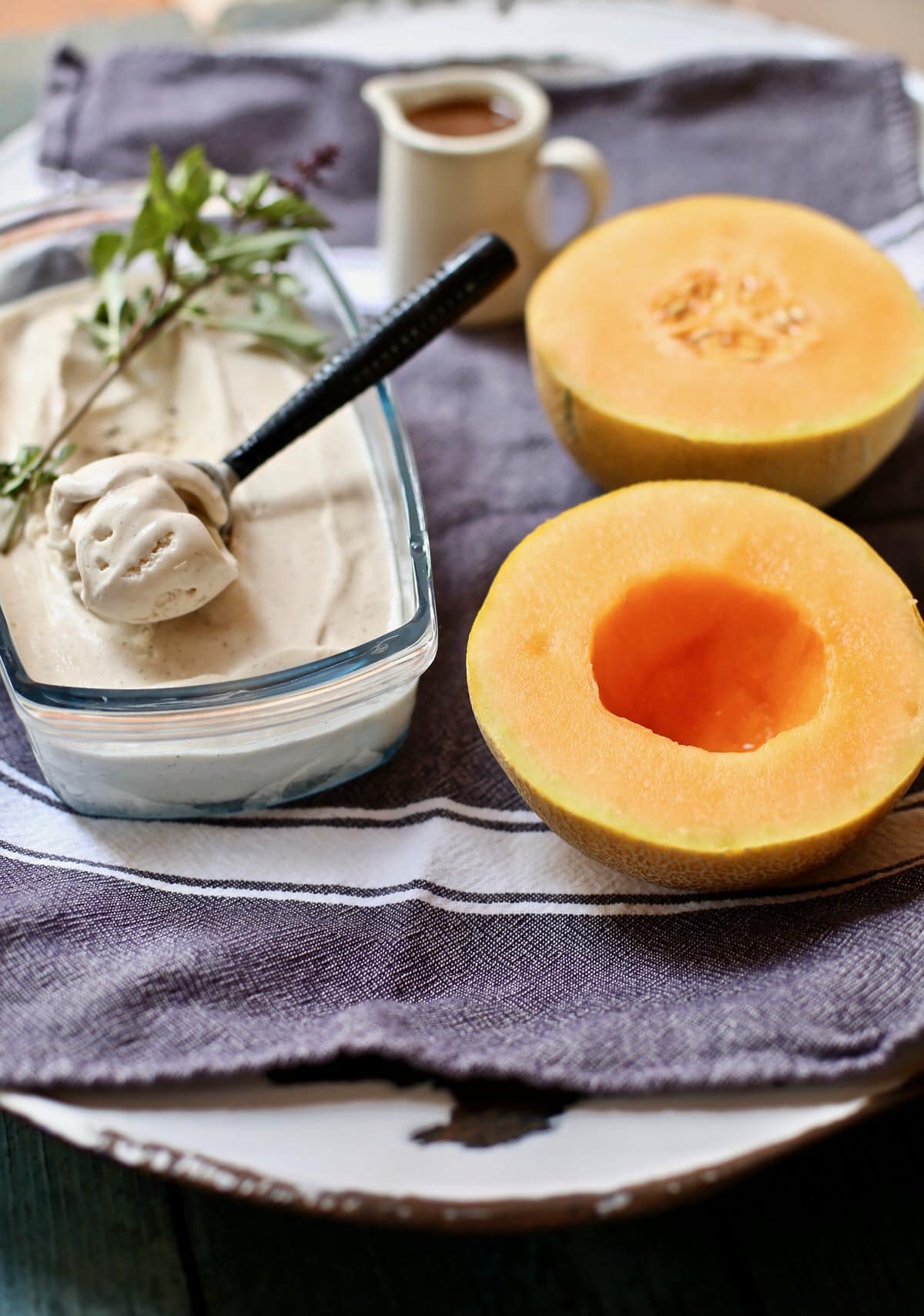two melon halves and some ice cream om a gray tablecloth
