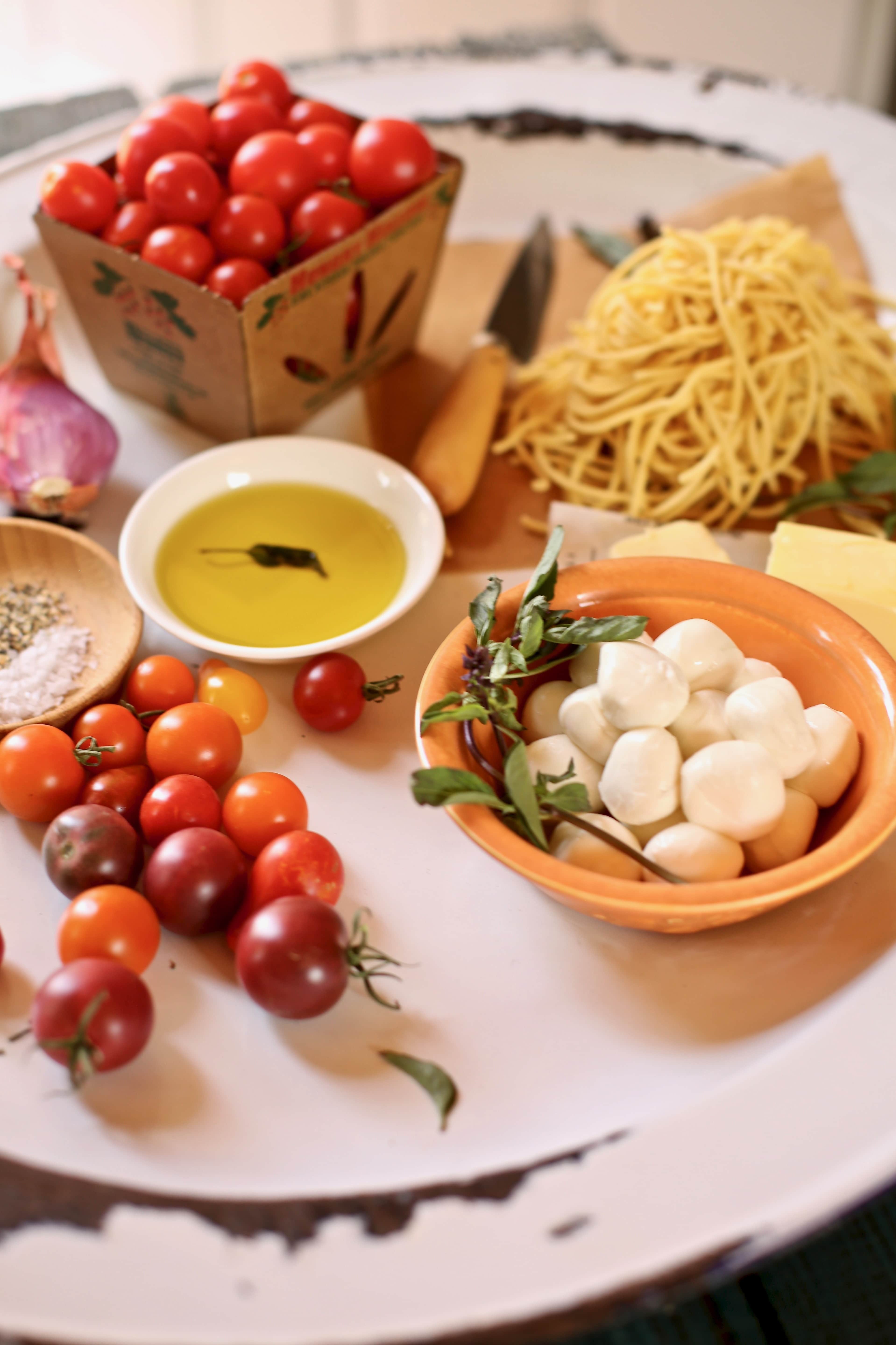 tomatoes and cheese and olive oil and pasta on a table for spaghetti