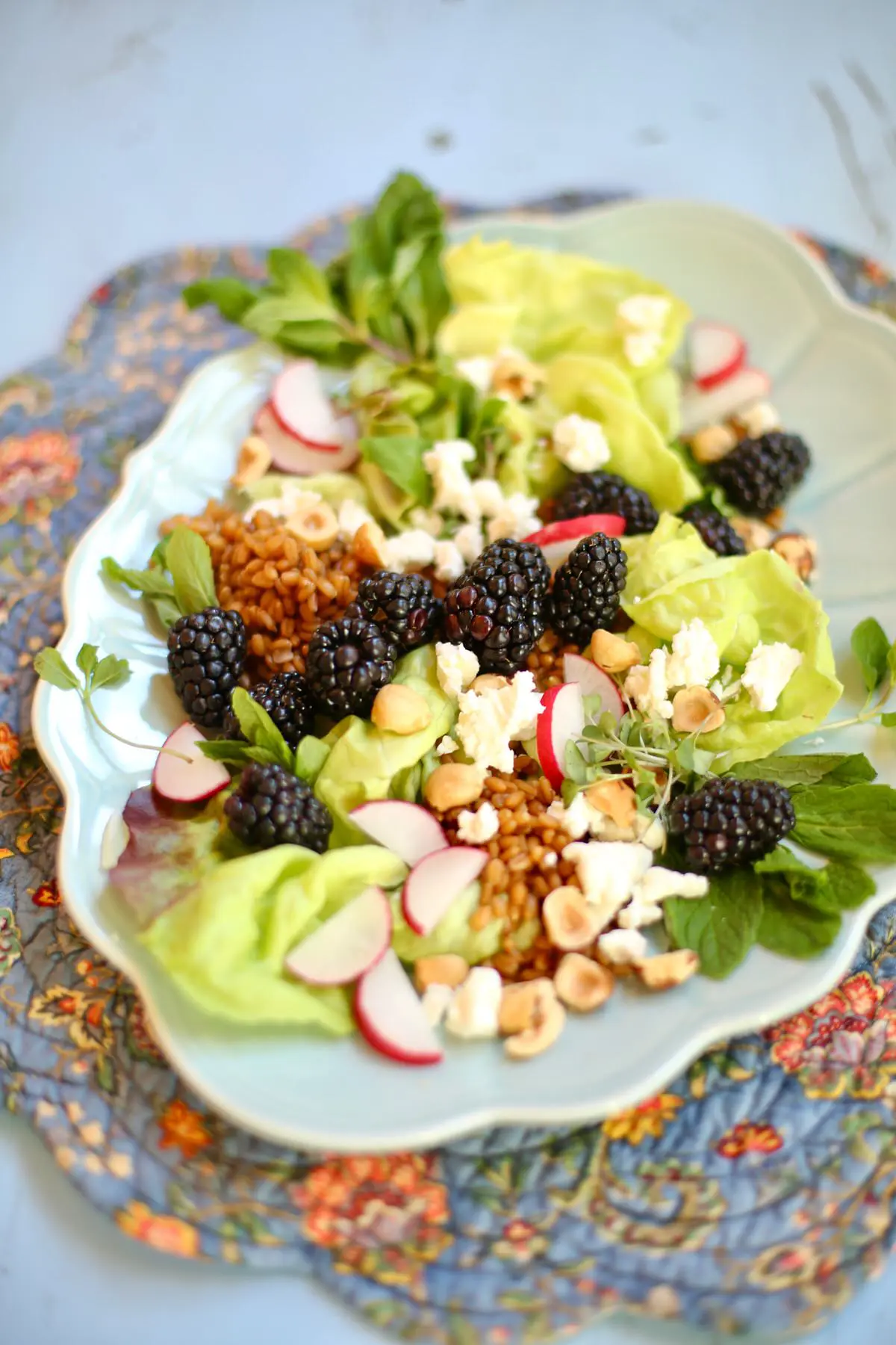 Blackberry, Goat Cheese, greens, radish and hazelnuts on a ling blue platter