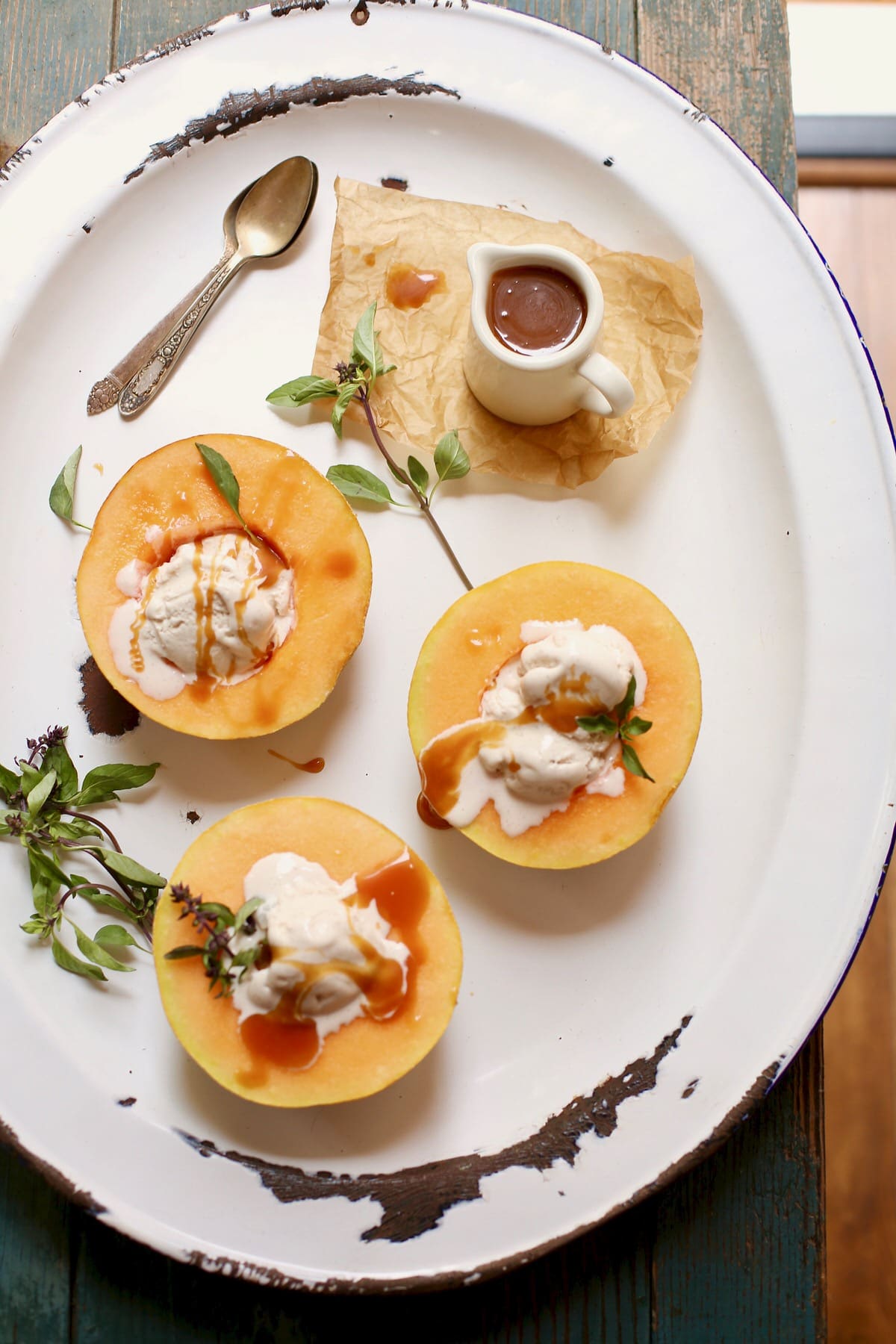 three melons with ice cream and caramel sauce on a white platter