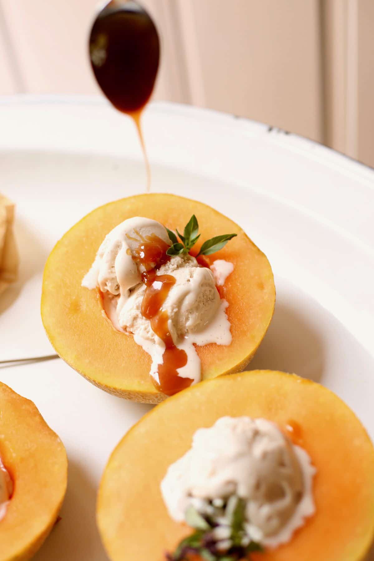 melon with ice cream and caramel sauce being poured over the top 