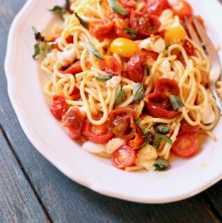 Pasta with tomatoes on a white plate and blue table