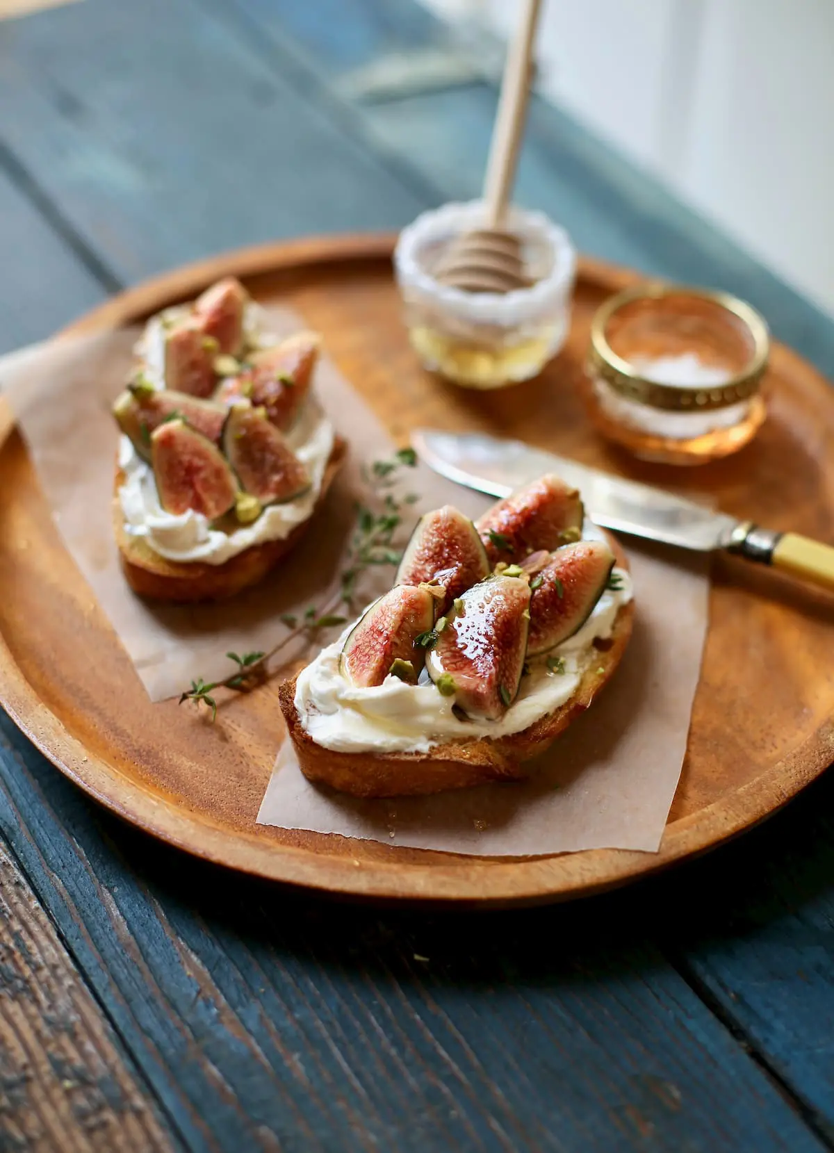 two toasts with figs on a wooden platter wotj knife and honey and salt