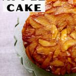 an apple cake on a green stand on a gray table cloth with a text box saying the name of the recipe.