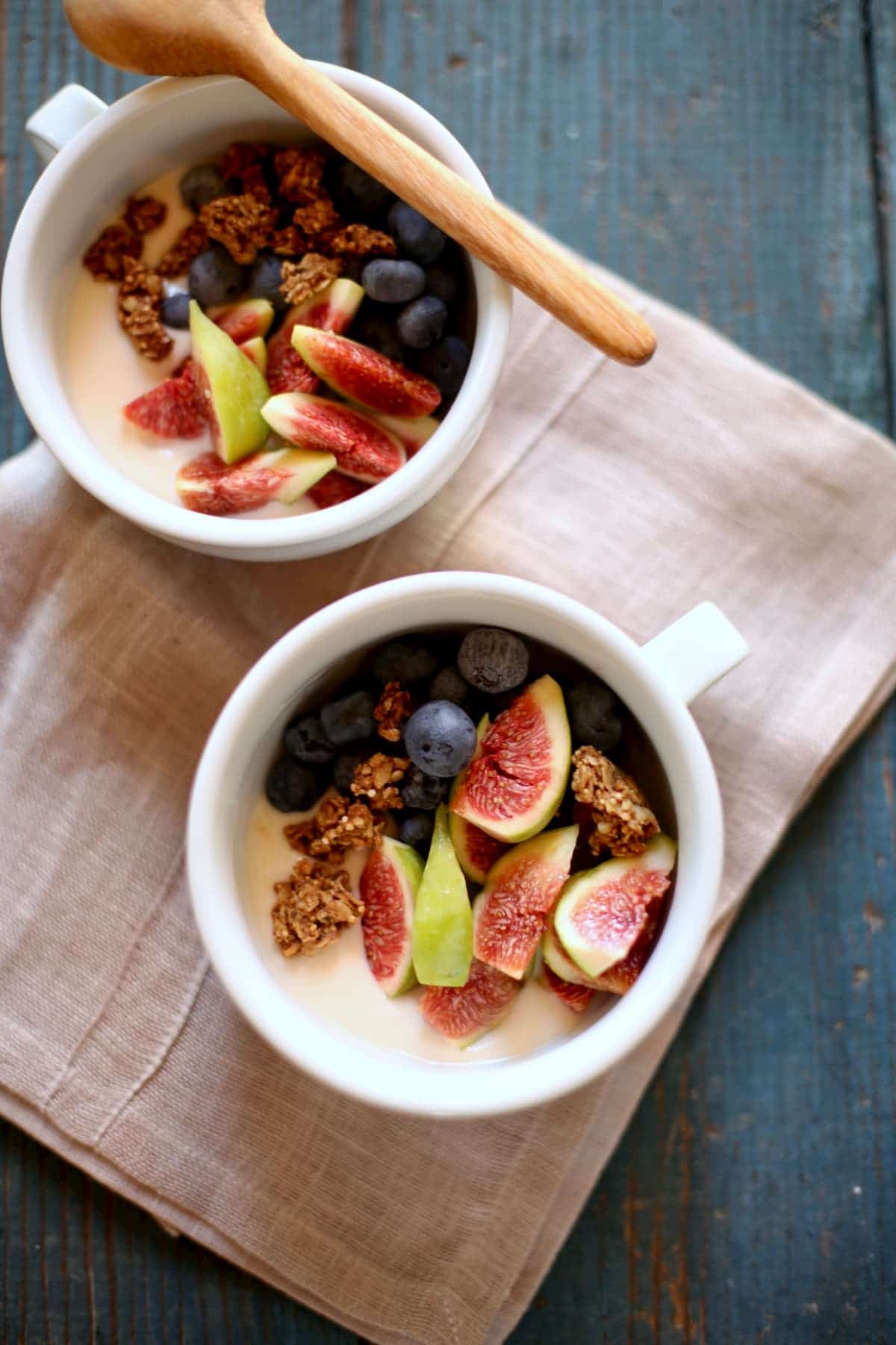 Two white bowls of graola, yogurt and fresh figs