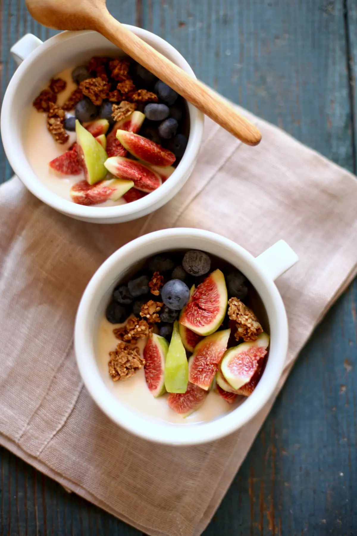 Two white bowls of graola, yogurt and fresh figs