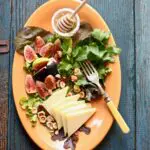 figs and cheese on an orange platter with text on a blue wooden table