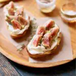 two fig toasts and honey on a wooden platter with text