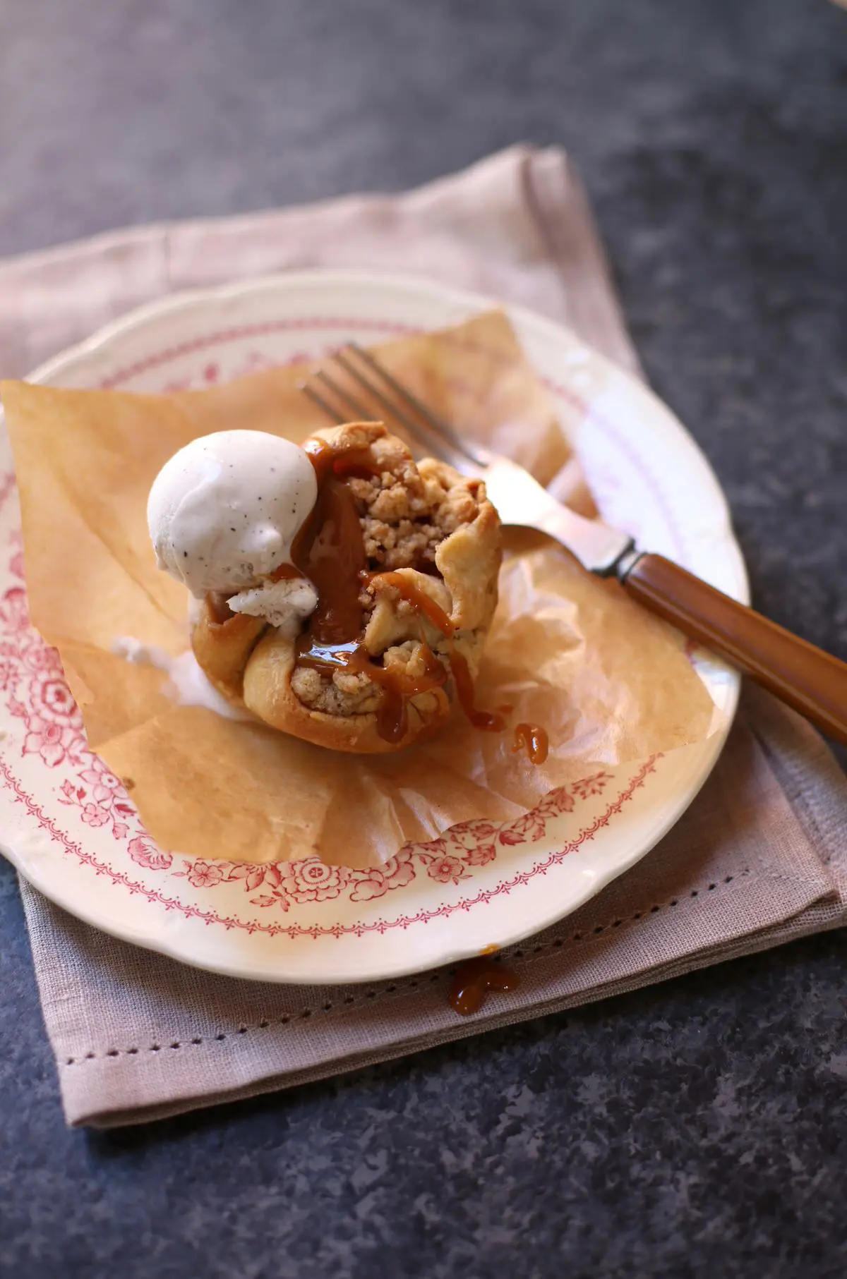 a small apple pie on a plate with a fork on a table