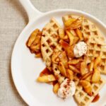 waffles and apples on a white platter with yogurt on top