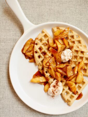 waffles and apples on a white platter with yogurt on top