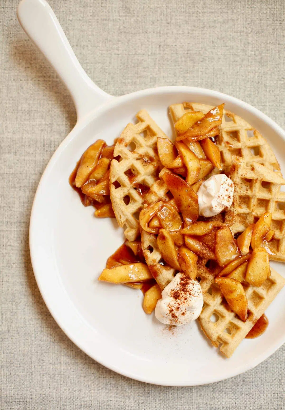 waffles and apples on a white platter with yogurt on top