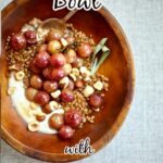 a big bowl of grapes, yogurt, nuts and sage and wheat berries on a gray tablecloth.