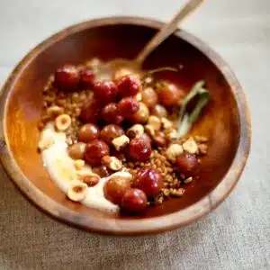 a wooden bowl of grapes and yogurt.