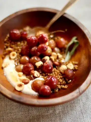 a wooden bowl of grapes and yogurt.