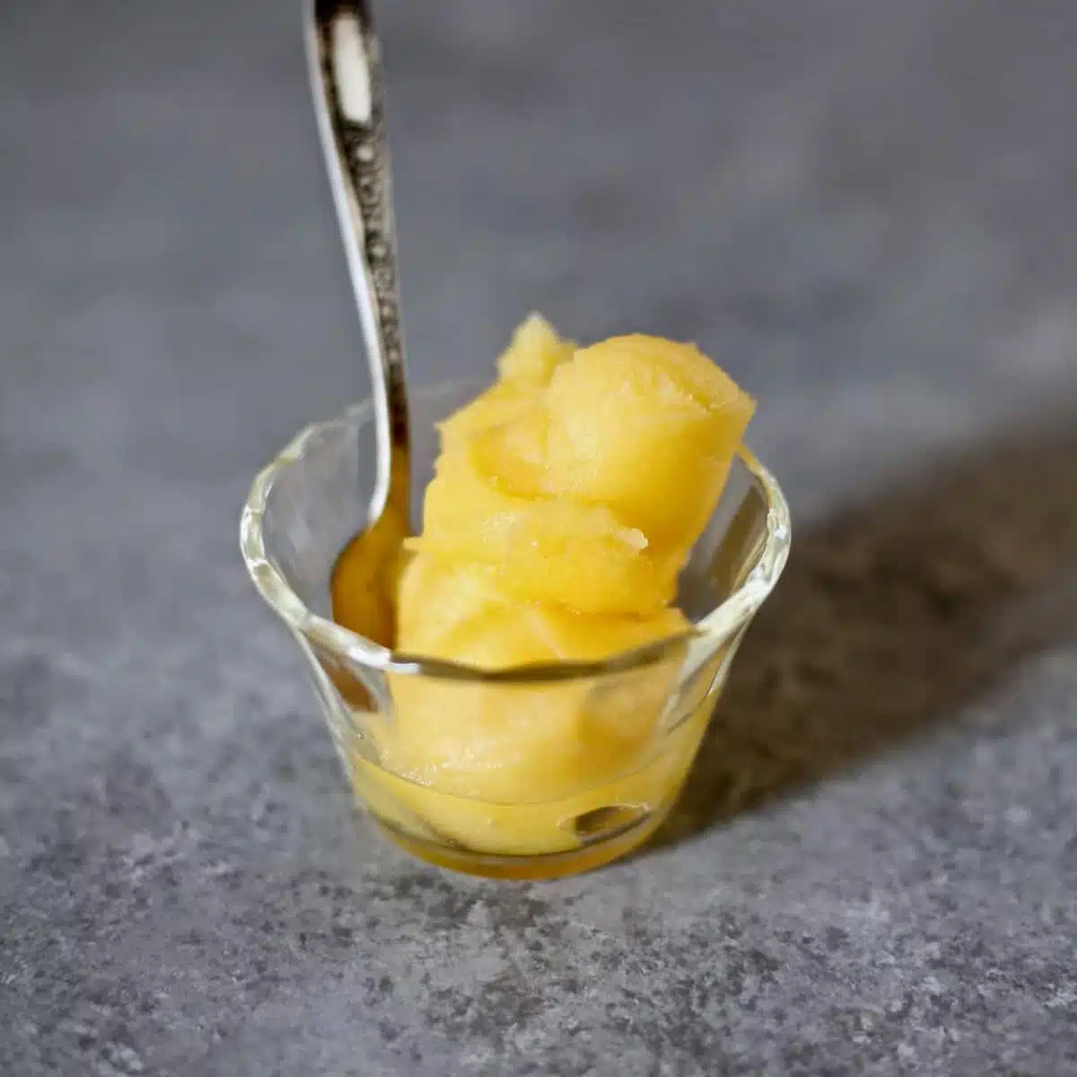 a small glass bowl of sorbet on a gray table.