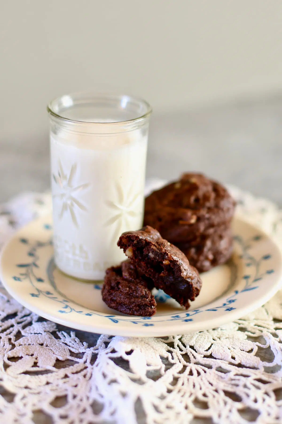 a couple of chocoalte cookies on a plate with a small glass of milk