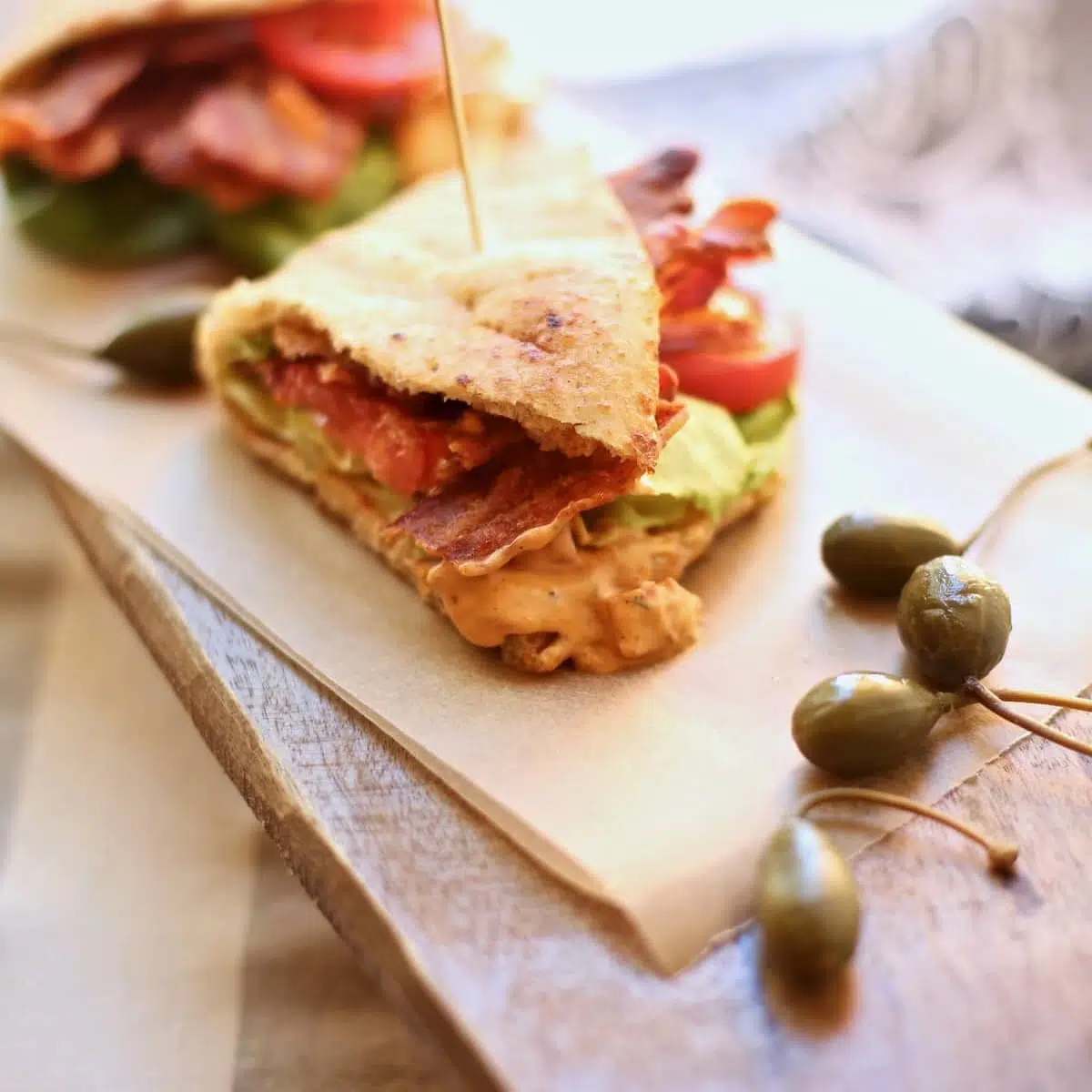 a square image of a naan sandwich on a wooden board.