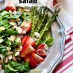 a silver plate with greens and asparagus and strawberries and almonds, with a text overlay saying the recipe name.