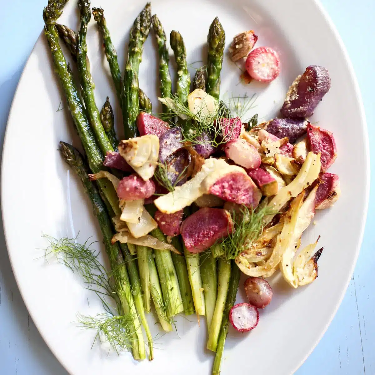 a white platter of roasted spring vegetables.