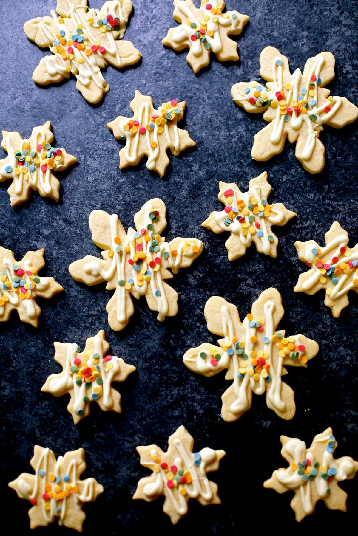 multiples of white chocolate snowflake cookies on a black board decorated