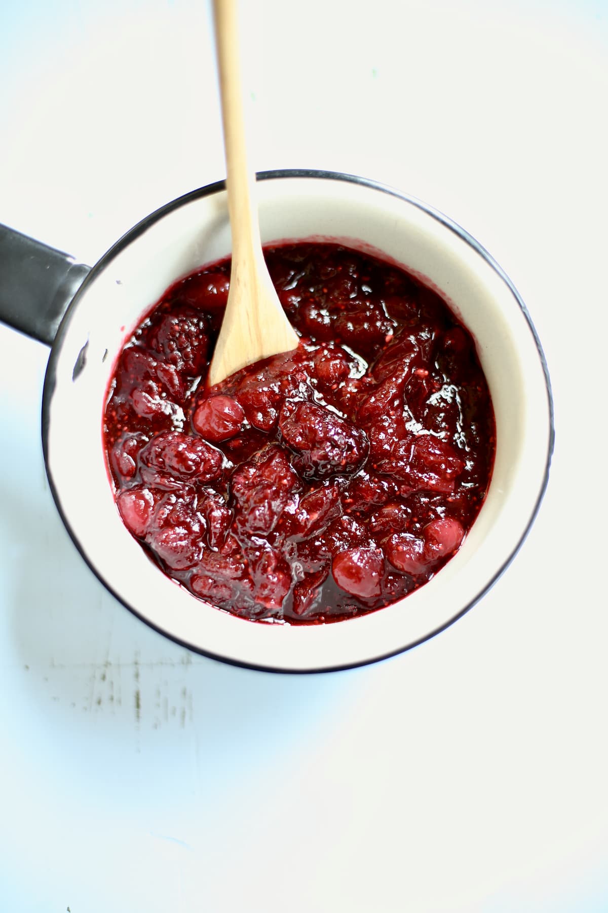 a white saucepan of made cranberry sauce on a blue table