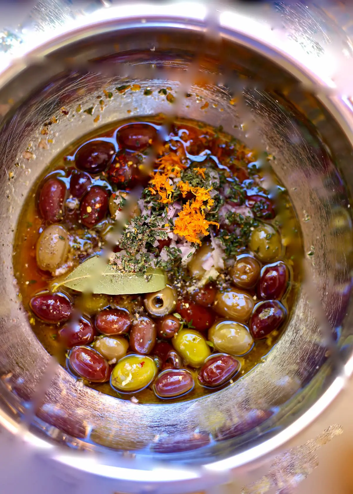 a bowl with seasonings and olives including thyme and bay leaf