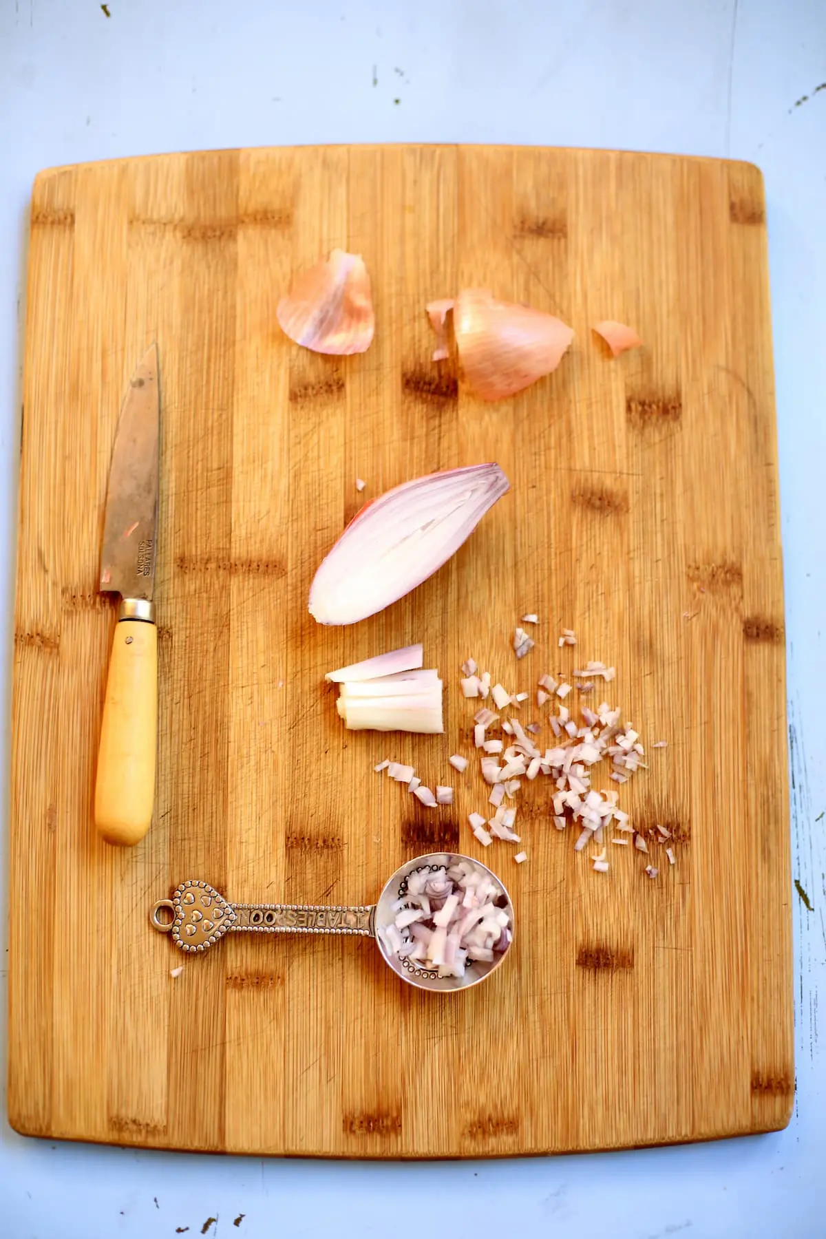 a knife and shallot on a cutting board with a tablespoon measurement 