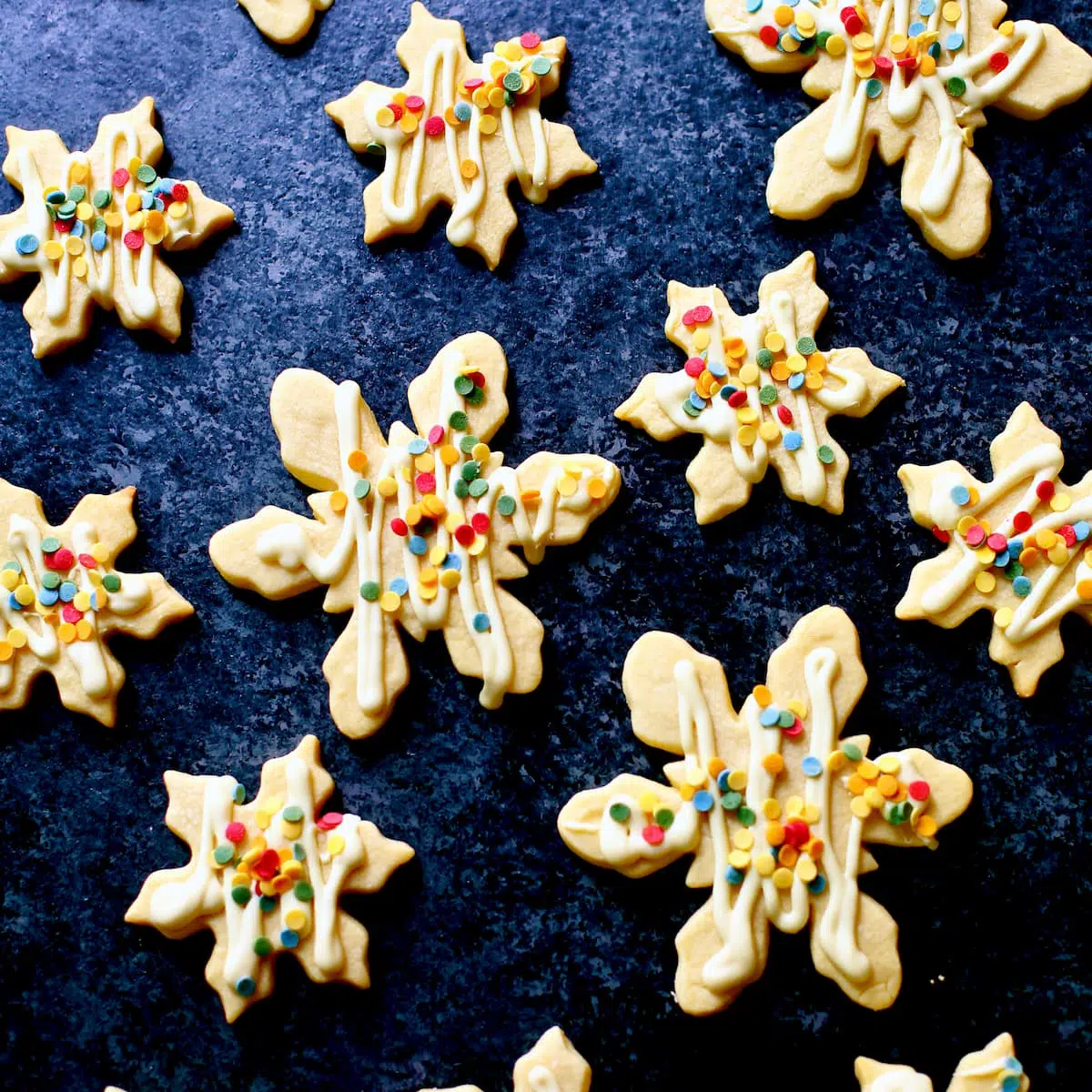 A square photo of snowflake cookies, drizzled in chocolate.