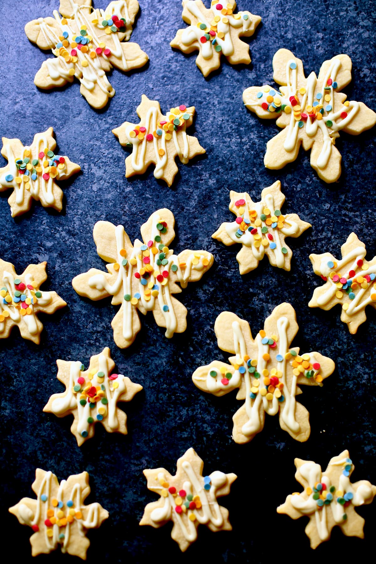 cookies shaped like snowflakes with chocolate drizzle and sprinkles.
