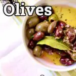 a bowl of party olives with bay leaf on a white tablecloth