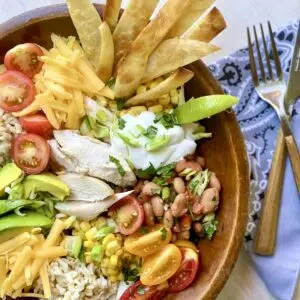 a close up photo of a burrito bowl with forks alongside.