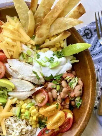 a close up photo of a burrito bowl with forks alongside.