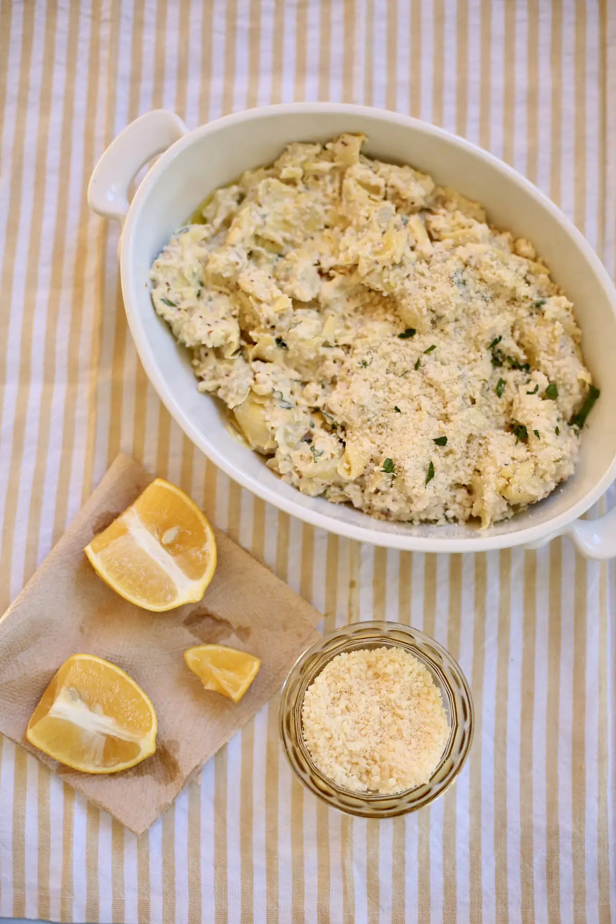 an unbaked artichoke dip with some cut lemons on the side