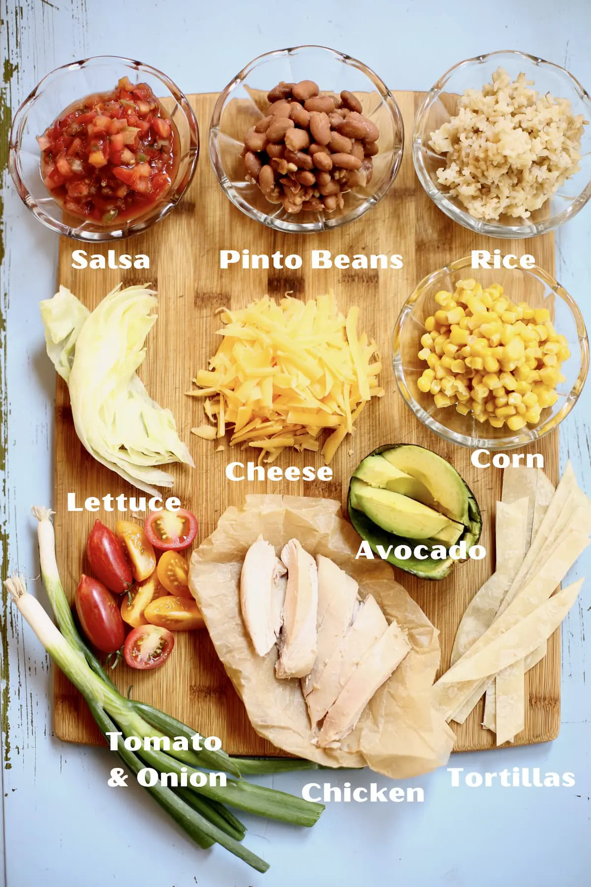 a cutting board of prepped ingredients for a meal,each one marked with text