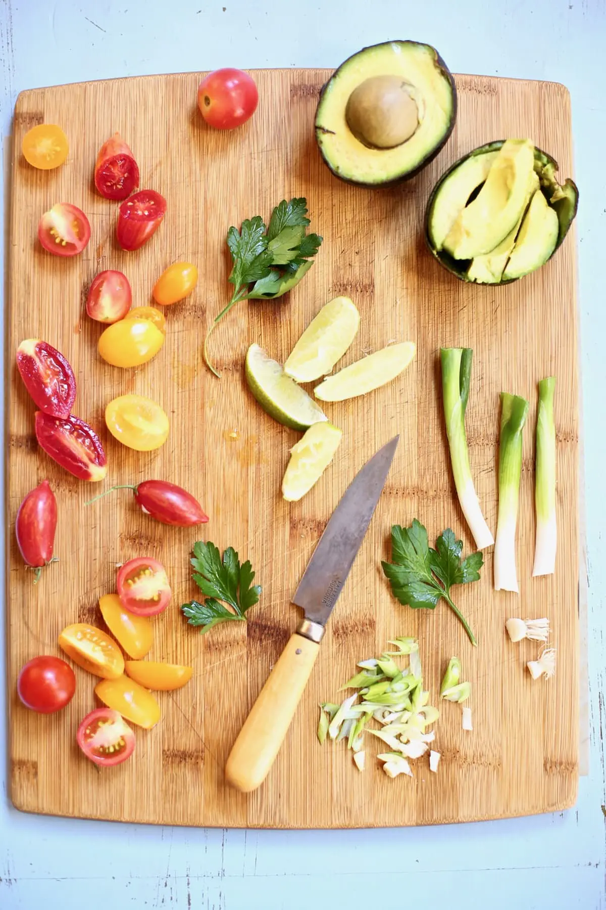 A cutting board of cut vegetables and a wooden knife