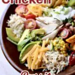 a bowl of chicken, cheese, avocado, rice, tomatoe and lettuce in a round wooden bowl with text overlay.