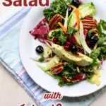 salad of greens blueberries pecans avocado and more on a white plate on a striped blue cloth.