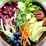 a wooden bowl of salad ingredients, with a text overlay sayign the recipe name "superfoods salad"