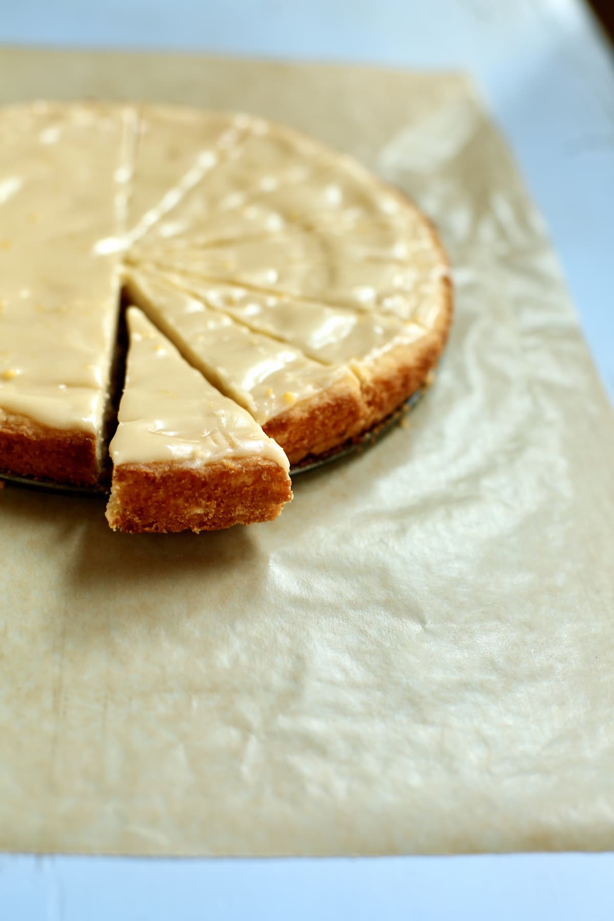 iced shortbread with a slice cut out, on a piece on parchment paper.
