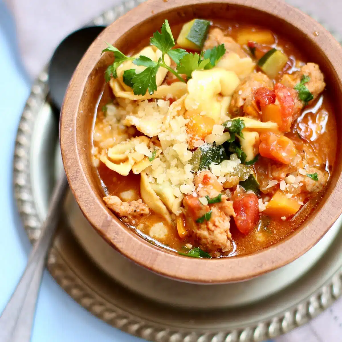 a wooden bowl of chicken sausage tortellini soup