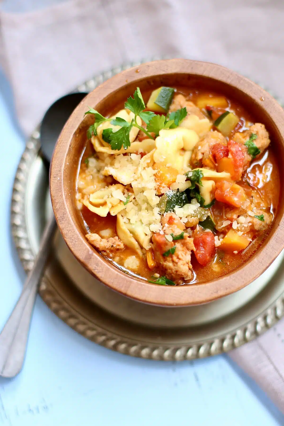 a bowl of chicken sausage soup in a wooden bowl.