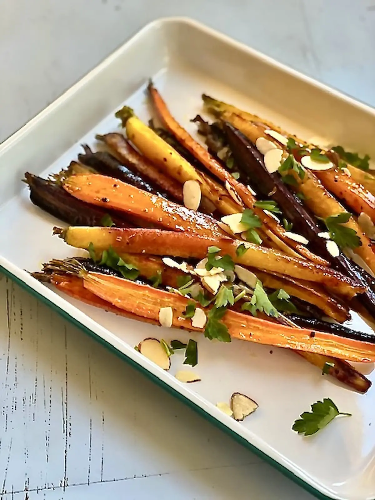 cooked carrots and almonds on a white serving tray